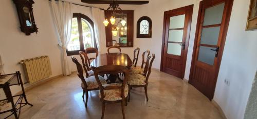 a dining room with a wooden table and chairs at Villa ROCAZUL in Jávea