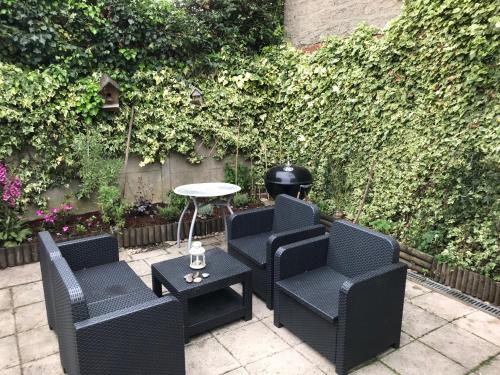 une terrasse avec des chaises, une table et une haie dans l'établissement Chez Lulu, à Montreuil