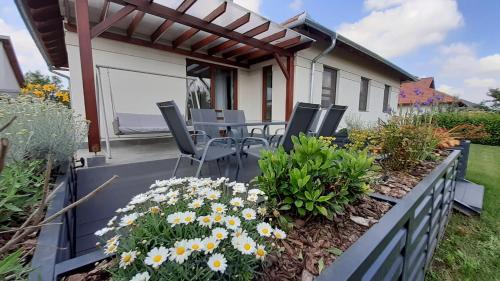 a patio with chairs and flowers on a house at Bíbic Apartman D in Kápolnásnyék