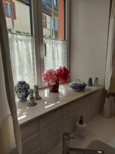 a window sill with vases and flowers in a bathroom at Romantisches Ferienhaus in Moselnähe in Maring-Noviand