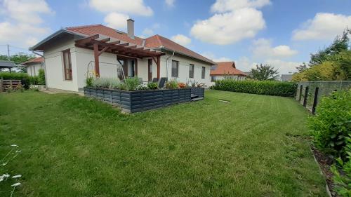 a house with a green lawn in front of it at Bíbic Apartman D in Kápolnásnyék