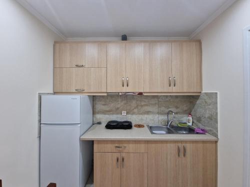 a kitchen with wooden cabinets and a white refrigerator at Vila Duro in Ksamil