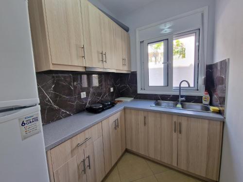 a kitchen with wooden cabinets and a sink and a window at Vila Duro in Ksamil