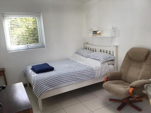 een kleine slaapkamer met een bed en een stoel bij The Blue Room in Bosham