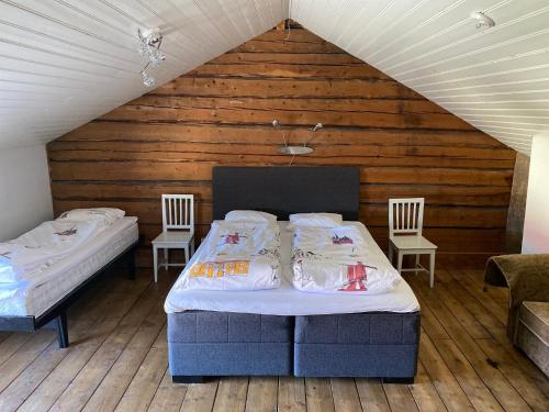 a bedroom with two beds and two chairs in a attic at Krepelin Apartments in Kristiinankaupunki