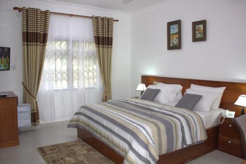 a bedroom with a bed and a window at Charlestina Beach Resort in Ampeni