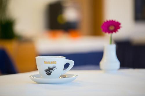 a coffee cup on a table with a vase with a flower at Hotel GH Kolinska in Bled
