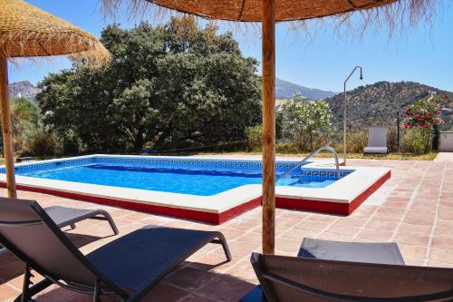 a swimming pool with chairs and an umbrella at Gusta la Vista in Ríogordo