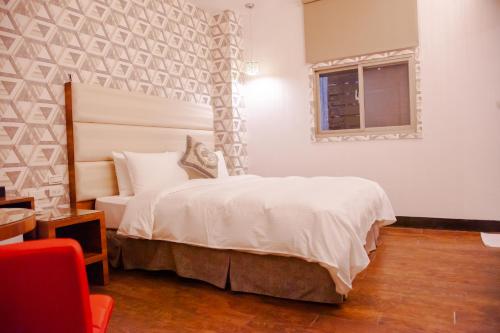a bedroom with a white bed and a window at E-Coast Star Hotel in Keelung