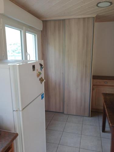 a kitchen with a white refrigerator and wooden cabinets at La Vinsonne in Glun