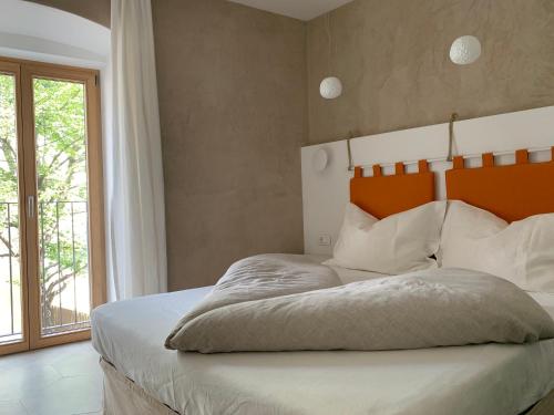 ein Schlafzimmer mit einem Bett mit einem orangefarbenen Kopfteil und einem Fenster in der Unterkunft Rennweg 114 in Meran