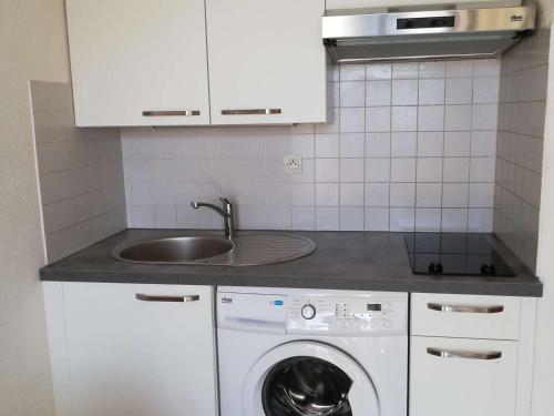 une cuisine avec un évier et une machine à laver dans l'établissement Studio Cabine 4 Pers avec Véranda et Parking Privé – Proche Quai de Plaisance à Marseillan - FR-1-326-489, à Le Castellas