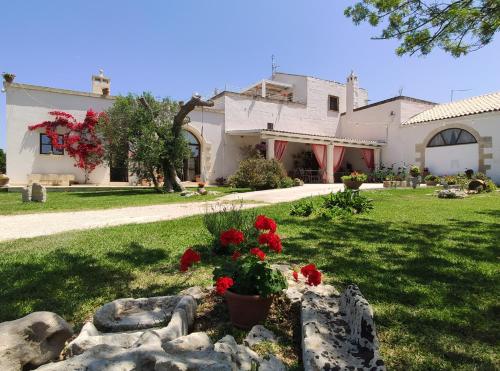 a house with red flowers in a yard at Masseria Salentina - Costarella in Borgagne