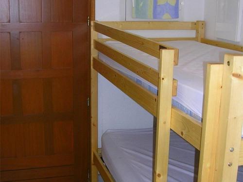 Ce lit superposé en bois se trouve dans un dortoir doté d'une porte. dans l'établissement Studio Cabine 4 Pers avec Véranda et Parking Privé – Proche Quai de Plaisance à Marseillan - FR-1-326-489, à Le Castellas