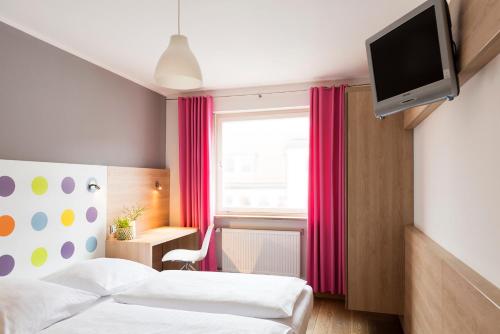 a hotel room with two beds and a flat screen tv at 1st Creatif Hotel Elephant in Munich