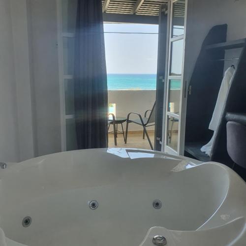 eine Badewanne in einem Zimmer mit Blick auf den Strand in der Unterkunft Verykokkos on the beach in Agia Anna