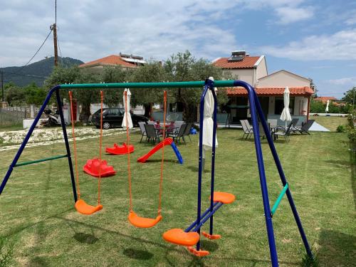 a swing set in a yard with orange swings at Harmony Studios & Apartments in Skala Potamias