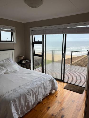 a bedroom with a bed and a view of the ocean at Makarios in Great Brak River