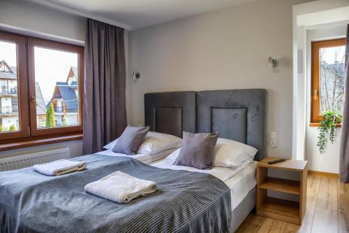 a bedroom with a large bed with two towels on it at Apartments Pod Jaworami in Białka Tatrzańska
