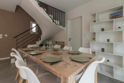 a dining room with a wooden table and white chairs at Les Villas de Castel - Villa Les frênes in Castelmaurou