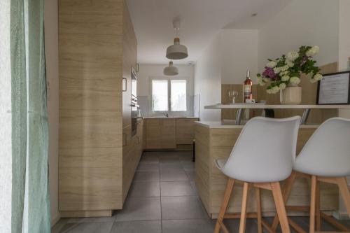 a kitchen with two white chairs and a counter at Les Villas de Castel - Villa Les frênes in Castelmaurou