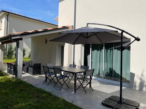 a table and chairs with an umbrella on a patio at Les Villas de Castel - Villa Les frênes in Castelmaurou