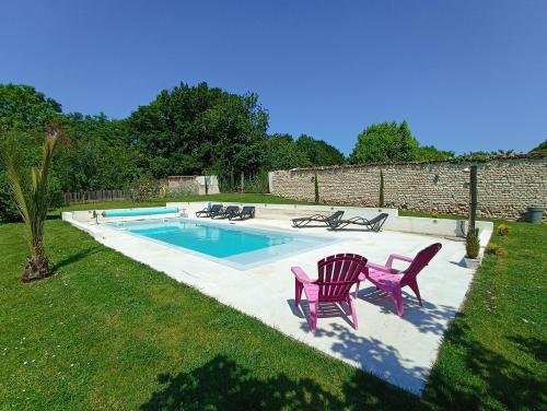 a swimming pool with two pink chairs at Gîte de charme dans ancienne seigneurie in Le Pin-Saint-Denis