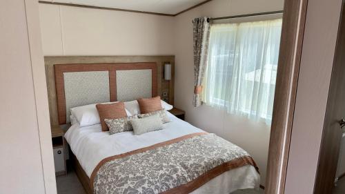 1 dormitorio con cama con almohadas y ventana en Luxury Hotub Lodge with Lake View at Tattershall Lakes en Tattershall