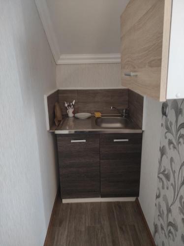 a small kitchen with a sink and wooden cabinets at Pokoje gościnne Cuma in Łeba