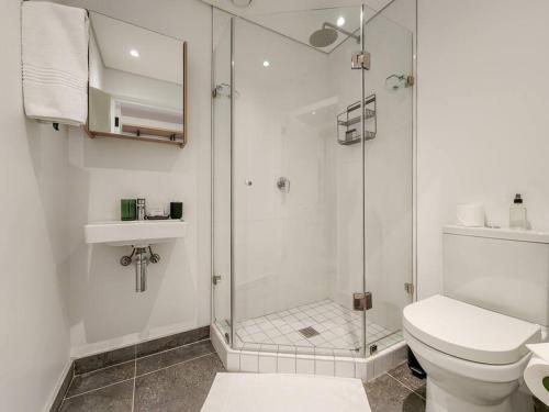 a white bathroom with a shower and a toilet at Secure Elegant Apartment Near Sea Point in Cape Town