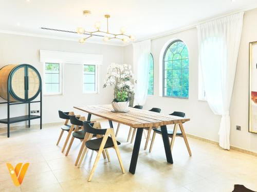 a dining room with a wooden table and chairs at Luxury 3BR Private Pool Villa and Elaborate Gardens in Dubai