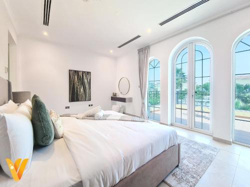a white bedroom with a large bed and large windows at Luxury 3BR Private Pool Villa and Elaborate Gardens in Dubai