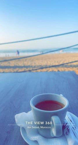 uma chávena de café sentada numa mesa perto da praia em الاسكندرية شاطئ النخيل em Alexandria