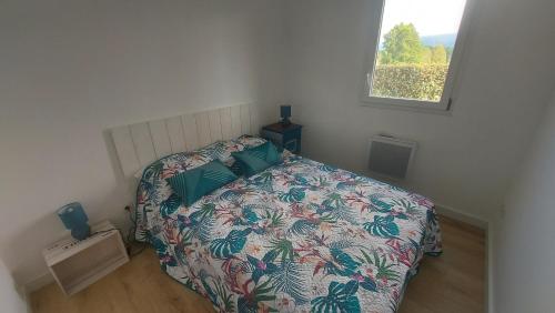 a bedroom with a bed with a floral bedspread and a window at Monfaucon vue sur les pyrenees in Pouzac