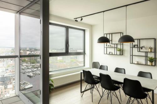 comedor con mesa, sillas y ventanas en UNIEK appartement -zicht Schelde en Amberes