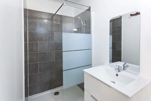 a white bathroom with a sink and a shower at L'escapade créole Jacuzzi Privatif Bungalow Vanille in Saint-Joseph