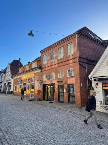 a man walking down a cobblestone street with buildings at Marken Apartments in Bergen