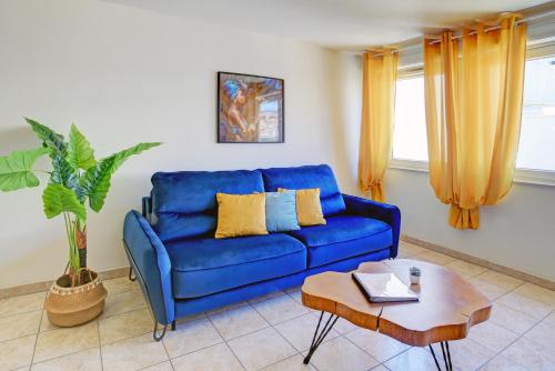 un canapé bleu dans un salon avec une table dans l'établissement Uncourtsejour - Montpellier gare - Parking, à Montpellier