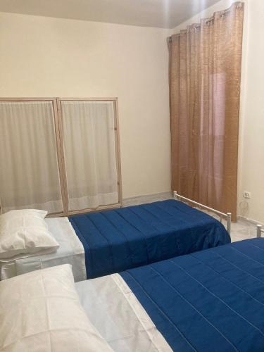a bedroom with two beds with blue sheets and a window at sentiti a casa-guest house in Naples