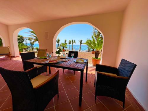 a dining room with a table and a view of the ocean at Casale fronte mare - villa with swimming pool in front of the beach in Porto Columbu - Perdʼe Sali