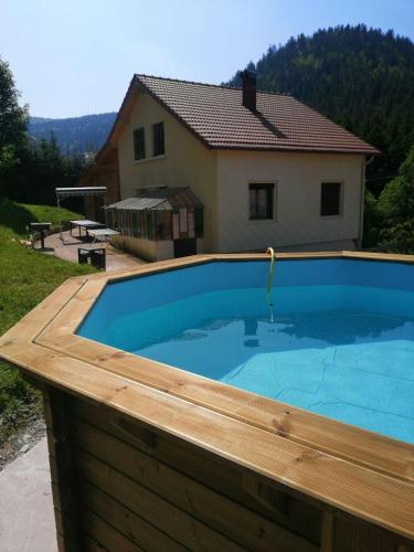une grande piscine avec une maison en arrière-plan dans l'établissement Gite de L'ours, à La Bresse