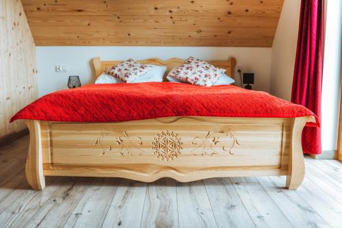a bedroom with a wooden bed with a red blanket at Apartamenty Widok Tatr in Zakopane