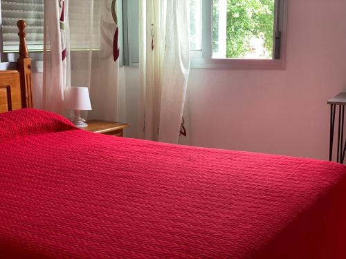 a red bed in a bedroom with a window at Hostal Mediterraneo in Torre del Mar