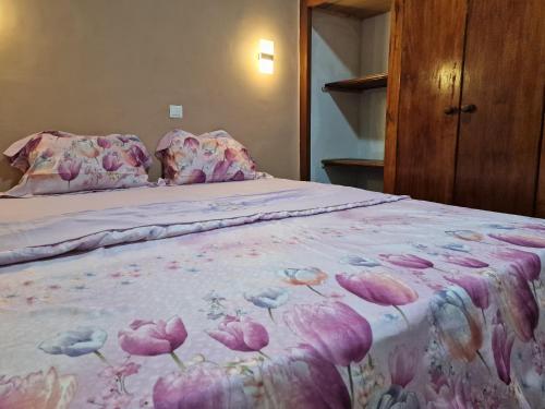 a bed with a pink bedspread with flowers on it at La Cité des Anges in Nkongsamba