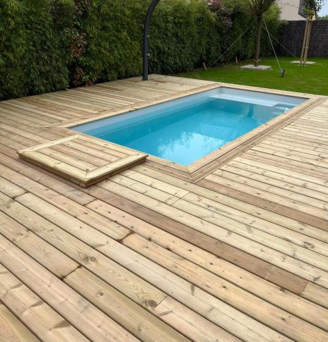 a swimming pool on a wooden deck at Charmante maison avec piscine in Beaussais sur Mer