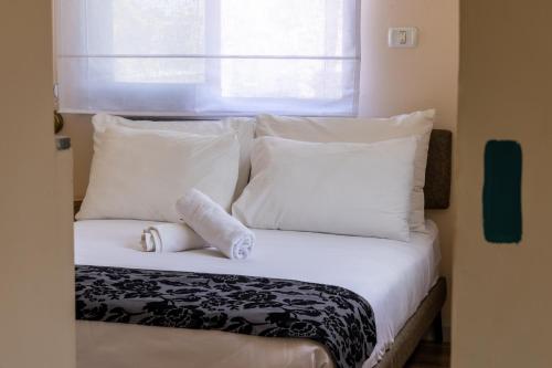 a bed with white pillows and a window at Domus Bat Galim Hotel in Haifa