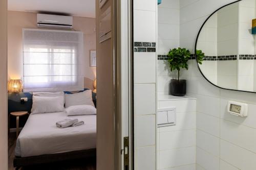 a small bedroom with a bed and a mirror at Domus Bat Galim Hotel in Haifa