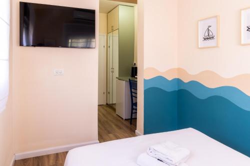 a room with a bed and a tv on a wall at Domus Bat Galim Hotel in Haifa