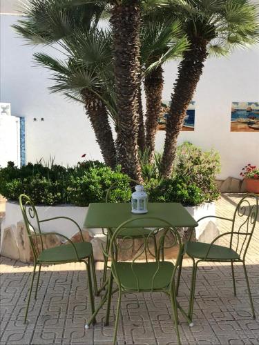 a green table and chairs with palm trees in the background at Mooie vrijstaande vakantiewoning met privé-zwembad in Miami Platja