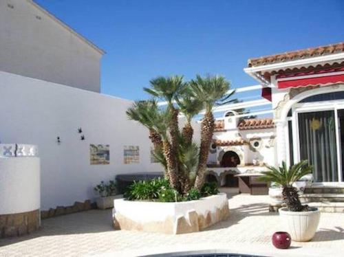 a house with palm trees in front of a building at Mooie vrijstaande vakantiewoning met privé-zwembad in Miami Platja